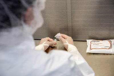 over shoulder shot of woman in white garment cleaning small bottle